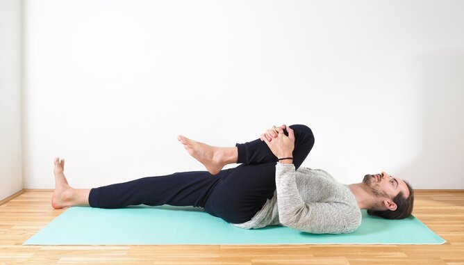 Yoga für einen gesunden Darm | © SONNENTOR Auf dem Foto ist ein Mann zu sehen, der Yoga für einen gesunden Darm ausführt. Er liegt auf dem Rücken. | © SONNENTOR